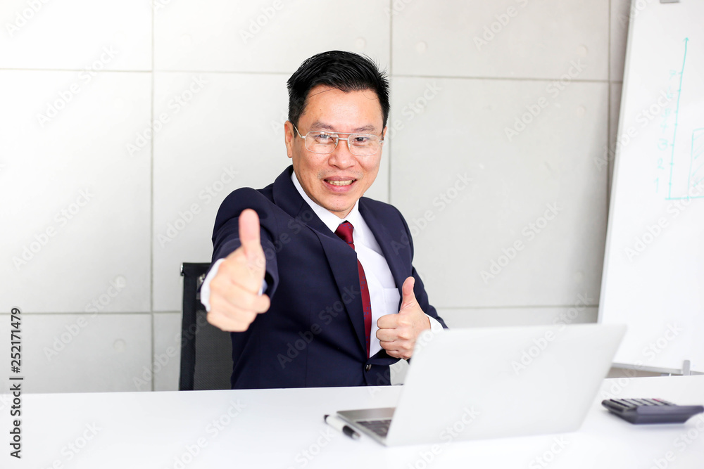 Successful confident businessman ,showing thumbs up or like sitting at office desk,success, good idea, great job business concept. Successful confident businessman ,showing thumbs up or like sitting at office desk,success, good idea, great job business concept.