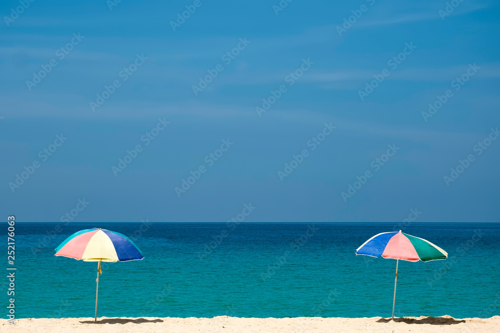 Raise an two beach umbrella on beautiful sunny day, clear sea and sky on background