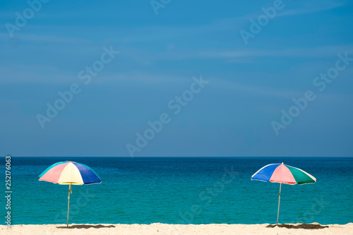 Raise an two beach umbrella on beautiful sunny day  clear sea and sky on background