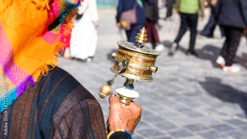 An old woman prayer with her mani wheel (hand prayer wheel) in Jokhang temple, Lhasa, Tibet, China. photo