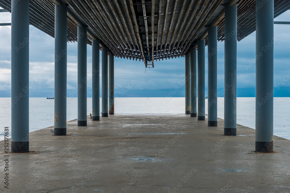 Pier under a canopy, a view of the sea and the gloomy autumn sky