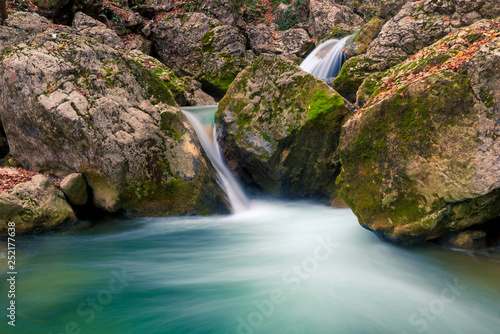 Beautifully flowing water between stones in the mountains, boulders covered with moss, beautiful nature