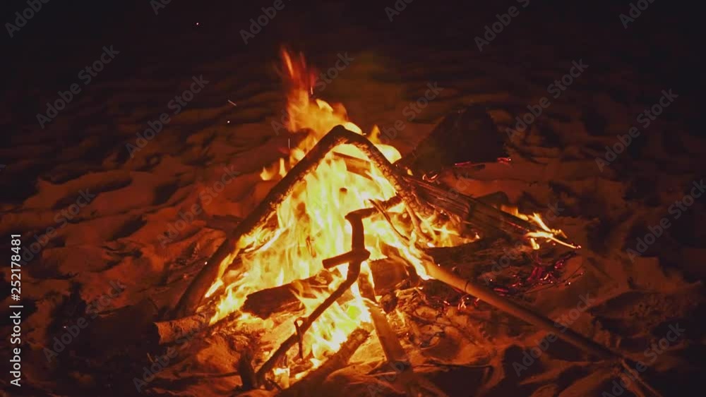 Blazing campfire on the beach during summer evening. Bonfire in nature as background. Burning wood on white sand shore at sunset. Tropical romantic landscape near sea water edge. Blazing campfire on the beach during summer evening. Bonfire in nature as background. Burning wood on white sand shore at sunset. Tropical romantic landscape near sea water edge.