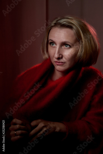Portrait of a middle-aged woman in the room. Photography in the Studio. Photo shoot in a dark key