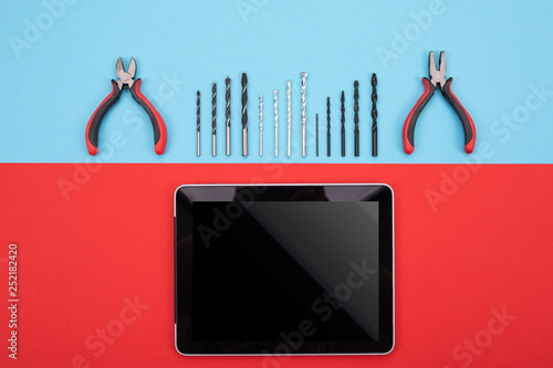 set of metalwork tools with tablet on colorful background photo