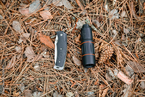 monocle and jackknife on the ground covered with pine needles photo