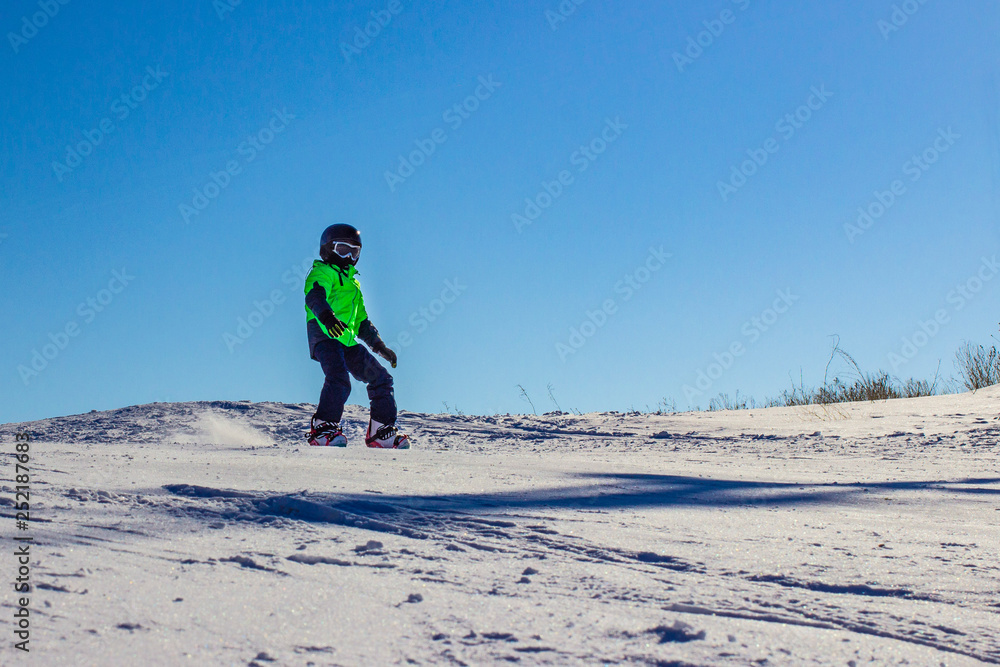 Kid on snowboard in winter sunset nature. Sport photo with edit space