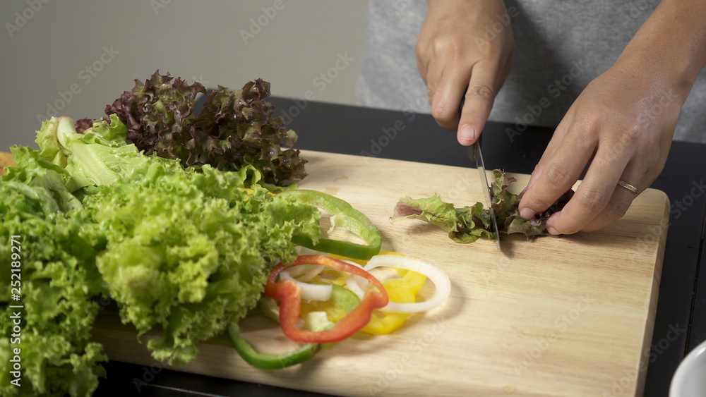 Woman cutting fresh salad vegetable for making salad.