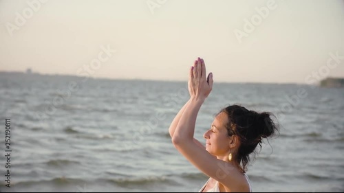 young woman practices yoga on the beach amid water and sunset, close-up. kundalini yoga