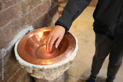 hand of the boy and the copper stew cup with the holy water