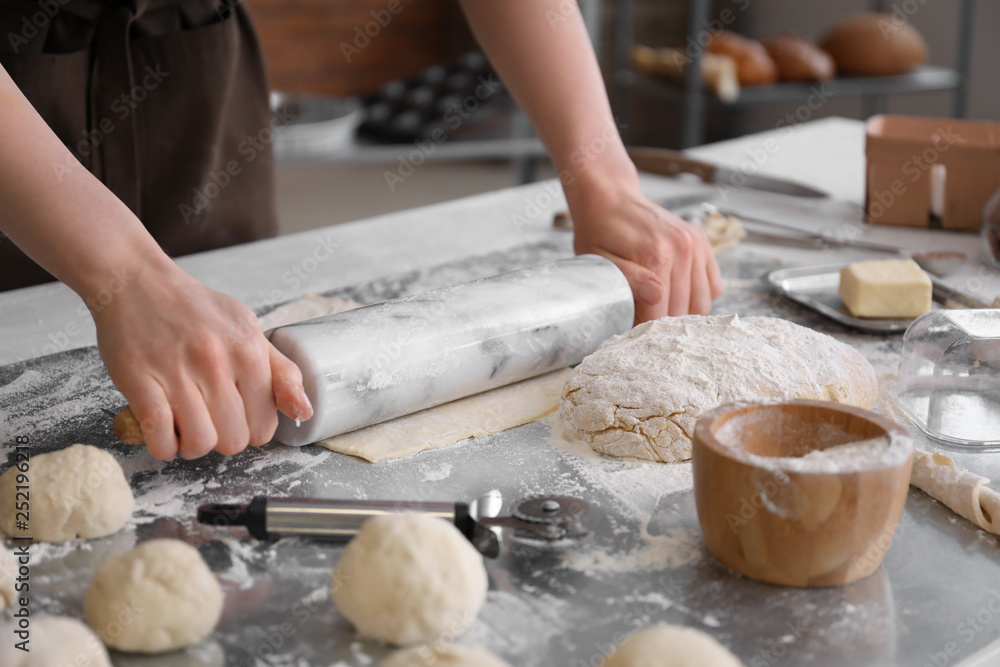 Female baker making dough for buns in kitchen