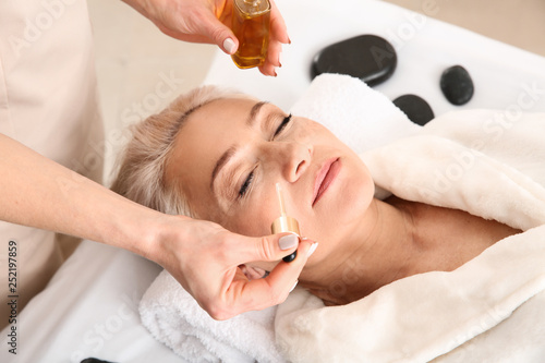 Photographie Mature woman undergoing treatment with face serum in beauty salon