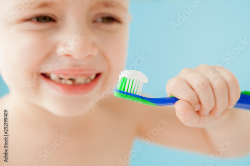 Portrait of little boy with toothbrush on blue background