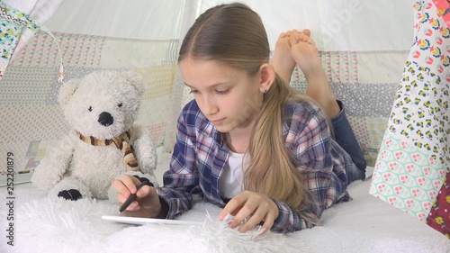 Fototapeta Naklejka Na Ścianę i Meble -  Child Playing Tablet in Playroom Girl Writing Homework for School Kid Playground