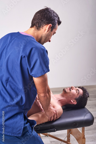 Young man having chiropractic shoulder adjustment. Physiotherapy, sports injury rehabilitation. Osteopathy, Alternative medicine, pain relief concept