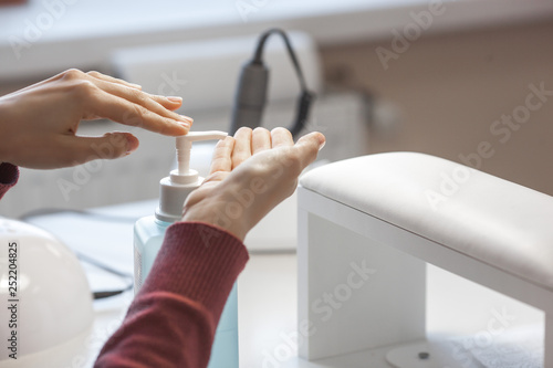 Woman desinfecting her hands before manicure procedure. Master preparing place for client. Hand care.