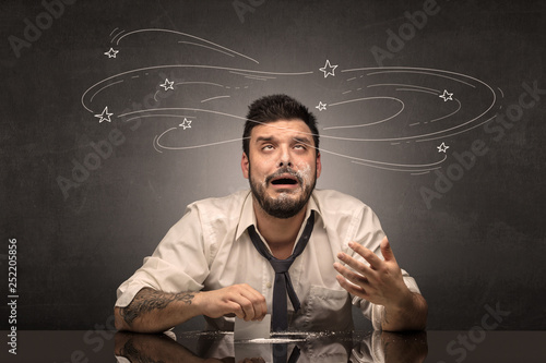 Young drunk man at his office with doodles around 