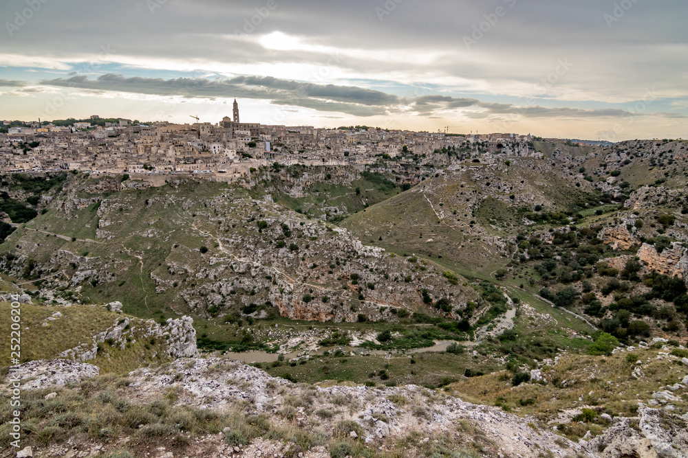 Amazing panoramic wide view of ancient town of Matera, the Sassi di Matera, Basilicata, Southern Italy, cloudy summer afternoon just before sunset