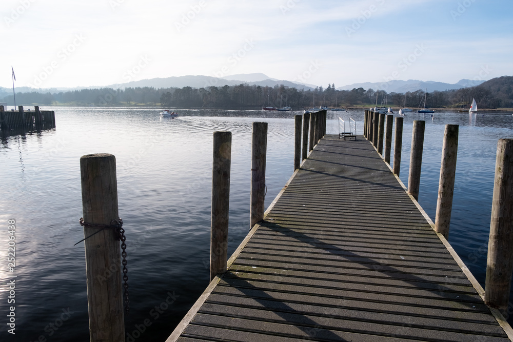 The pier at Ambleside Waterhead on a clear day looking over the Great Langdale skyline, Lake District, UK