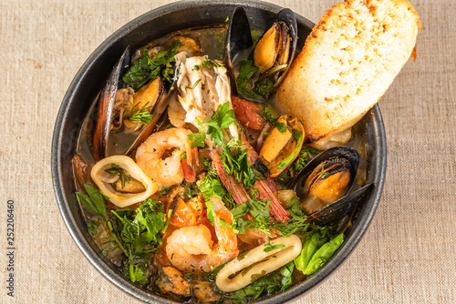 Photography Homemade cioppino in a bowl and toast, top view - Italian-American seafood soup - fish, mussels, shrimp and squid