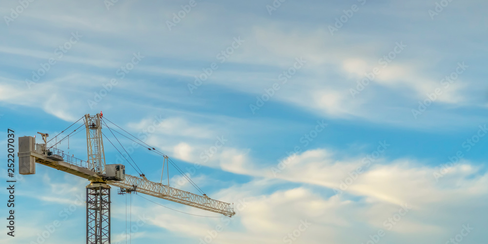 Tower crane against blue sky with puffy clouds Tower crane against blue sky with puffy clouds