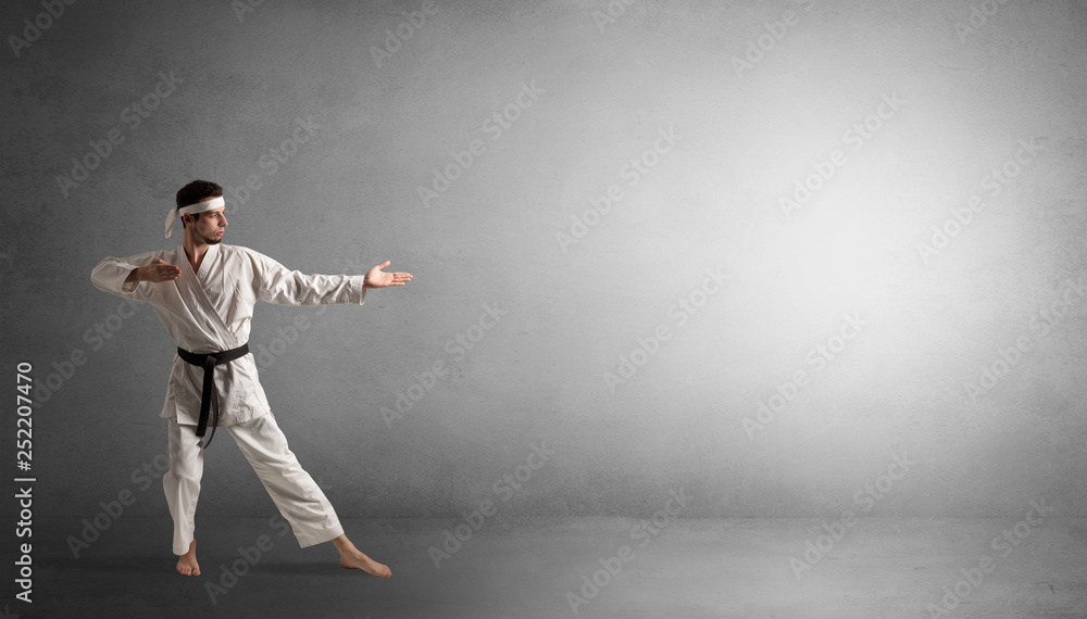 Small karate man fighting in an empty grey copy space