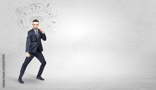 Young businessman in suit fighting with doodled symbols concept 