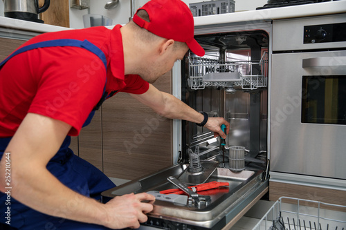 Billede på lærred home appliance maintenance - repairman repairing dishwasher in kitchen