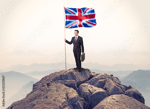 Successful businessman on the top of a mountain holding victory flag   © ra2 studio