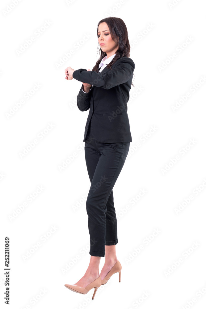 Serious business woman checking time on wrist watch waiting for appointment. Full body isolated on white background. Serious business woman checking time on wrist watch waiting for appointment. Full body isolated on white background.