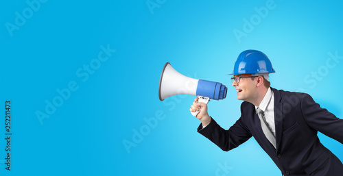 Young architect constructor yelling with megaphone and copyspace