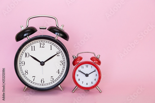 Two alarm clocks on a pink color background with free space for text