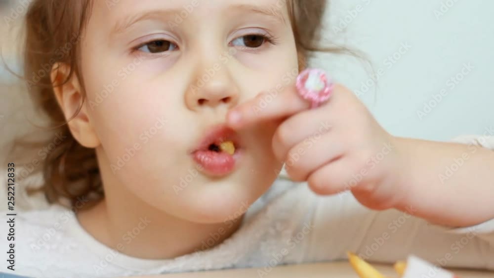 Child girl eating french fries in the fast food cafe. Portrait closeup baby who eats food. Child girl eating french fries in the fast food cafe. Portrait closeup baby who eats food.