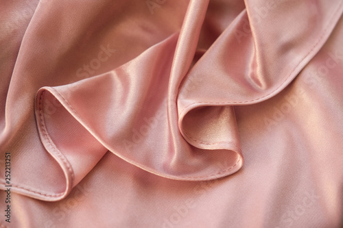 Close up fabric. The silk fabric is laid out waves. Pink sateen fabric for background or texture.