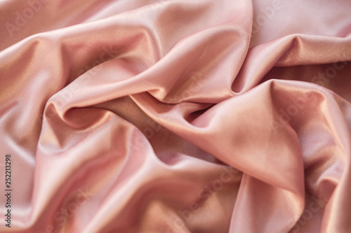 Close up fabric. The silk fabric is laid out waves. Pink sateen fabric for background or texture. photo