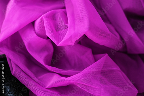 Close up pink fabric. The purple fabric is laid out waves. Fuchsia sateen fabric for background or texture.