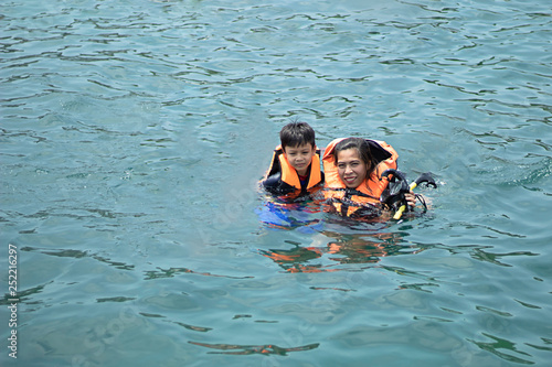 Woman and boy wearing a life jacket, scuba diving in the sea.