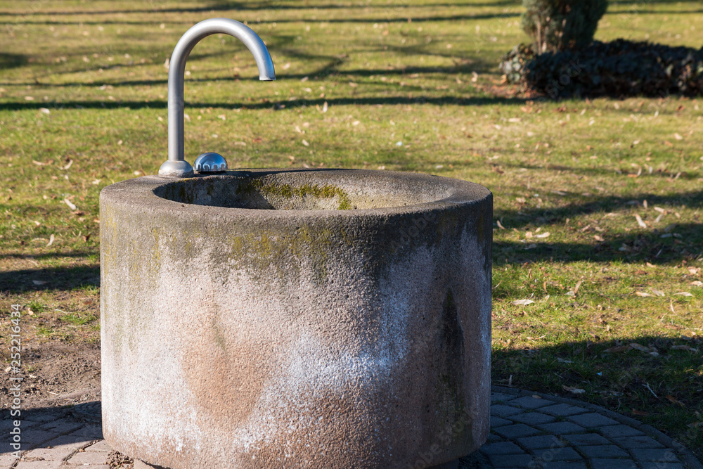 Concrete fountain with water dispenser in a park
