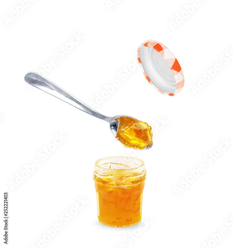 Foto Spoon with tasty apricot jam on white background