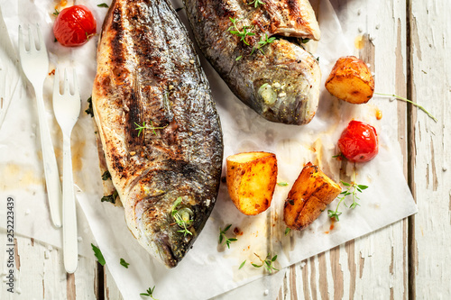 Homemade potatoes and seabream with tomatoes on white table