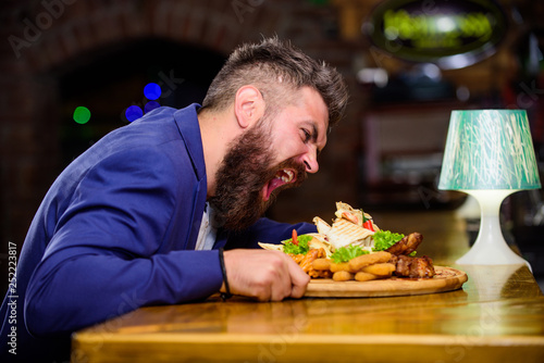 Cheat meal concept. Hipster hungry eat pub fried food. Manager formal suit sit at bar counter. Delicious meal. Man received meal with fried potato fish sticks meat. High calorie snack. Enjoy meal photo