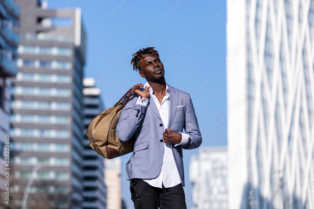 Front view black young man urban casual fashion in the street. Wearing  black elegant jacket, jeans, holding and carrying a bag in a sunny day  Stock Photo | Adobe Stock