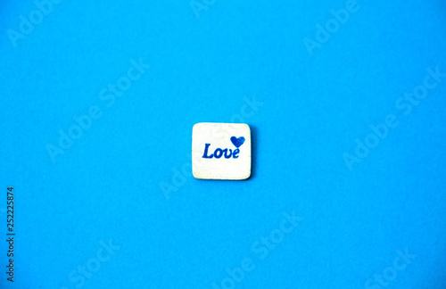 White square wood with love word written on blue sky background, love concept.
