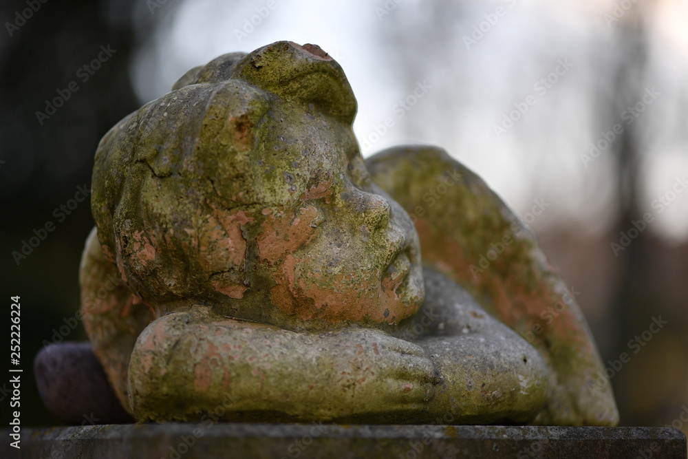 A moss covered sandstone sculpture of an angel. A moss covered sandstone sculpture of an angel.