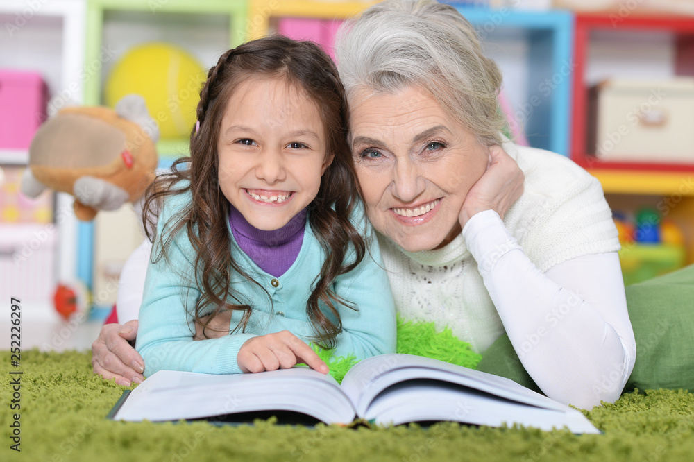 Portrait of grandmother reading book with granddaughter Portrait of grandmother reading book with granddaughter