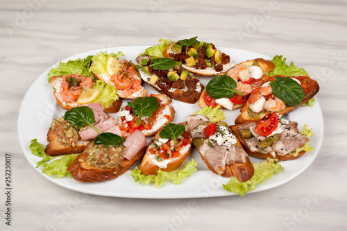 Meat sandwiches with vegetables in an assortment on a white dish.