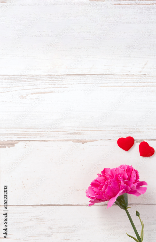 May mothers day concept photography - Beautiful carnations and hearts shape with white empty card isolated on a bright wooden table, copy space, flat lay, top view, mock up