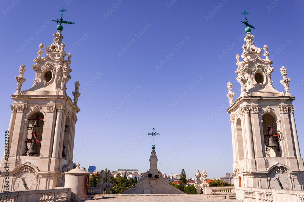 Obraz premium Imposing baroque towers of Monastery of Sao Vicente de Fora, with crosses and bells, as seen from the roof, in Lisbon, Portugal, at sunset, with blue pink skies, during a church visiting tour.