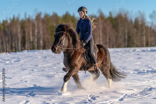 Young Swedish woman riding her Icelandic horse in deep snow