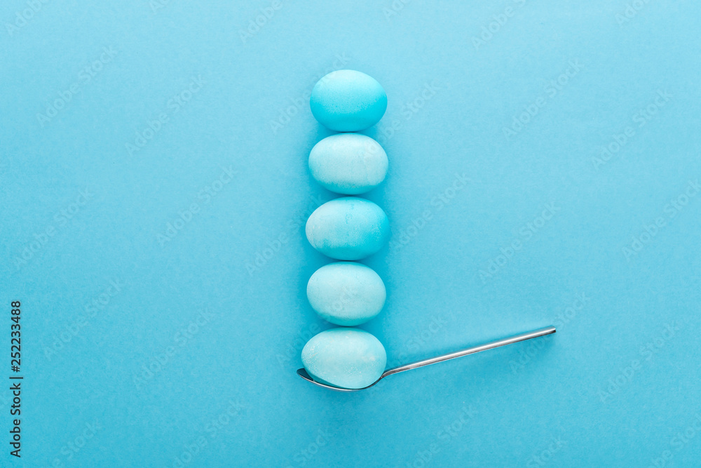 top view of blue easter eggs on spoon isolated on blue top view of blue easter eggs on spoon isolated on blue